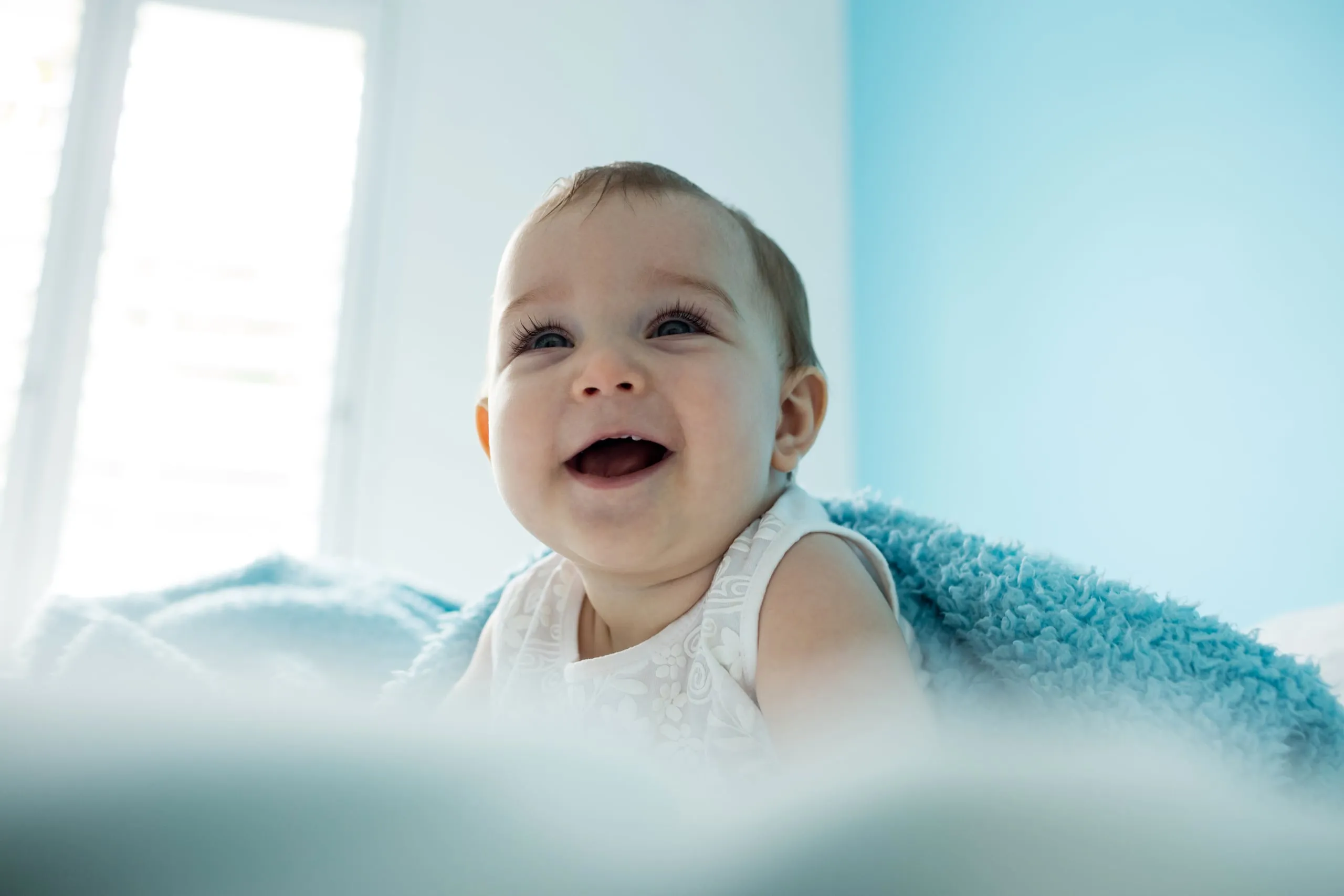 A laughing baby on a soft blue blanket