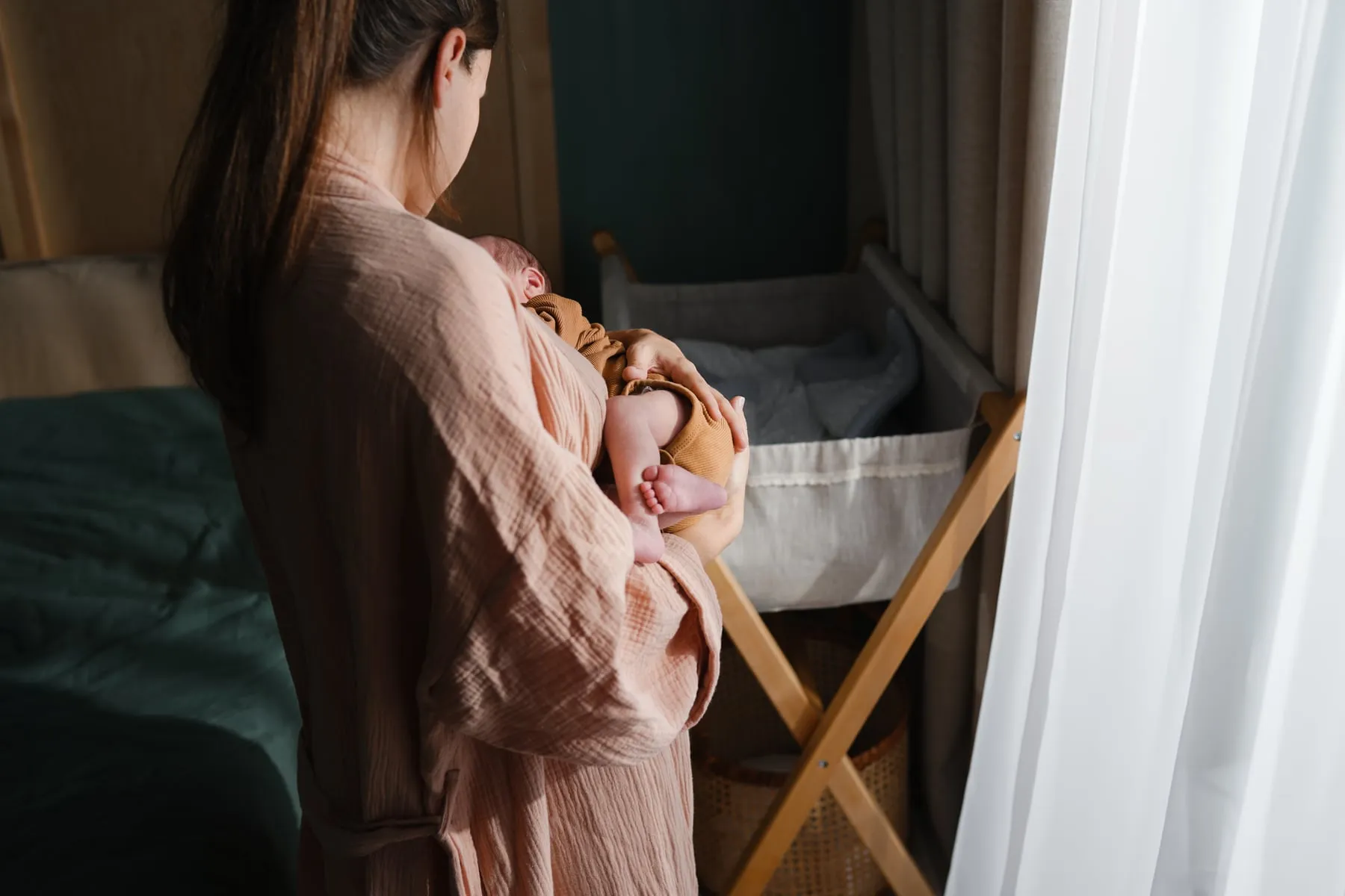 A mother feeding her baby by the window on a winter day